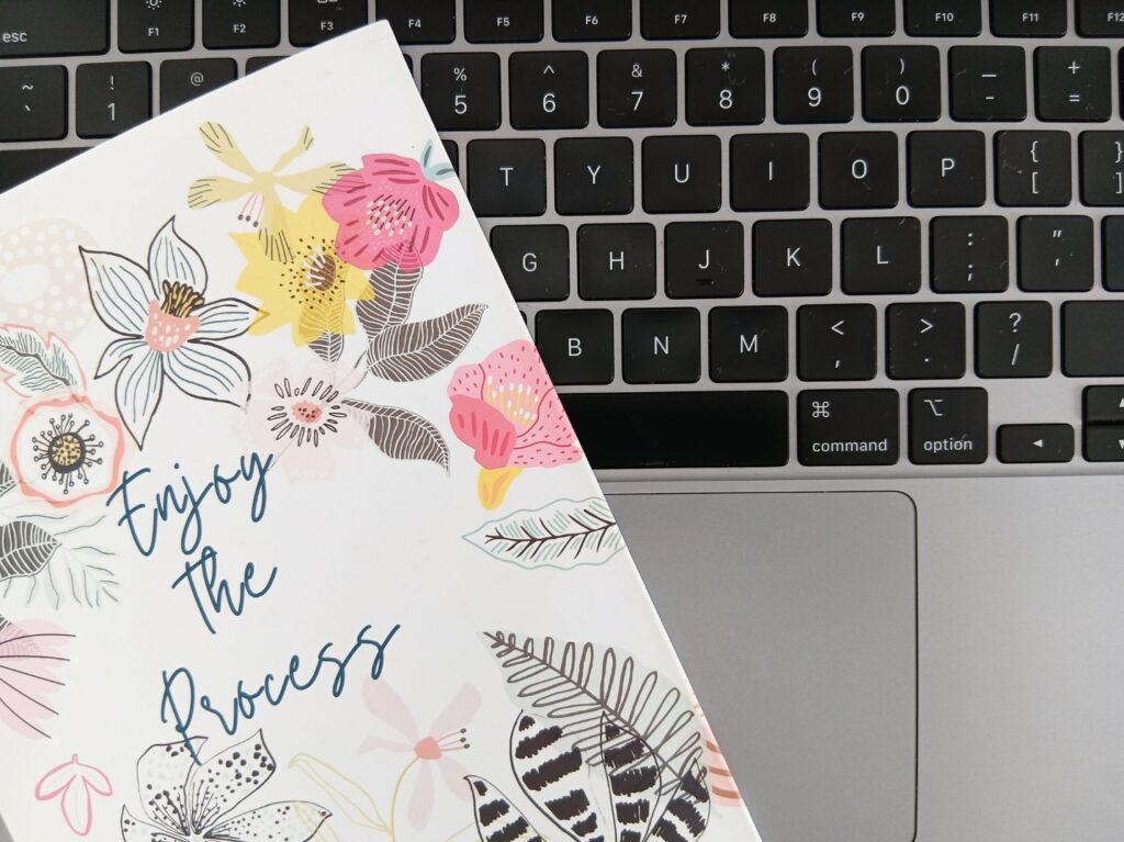 Notebook with "Enjoy the Process" text on a laptop keyboard, representing creative website planning