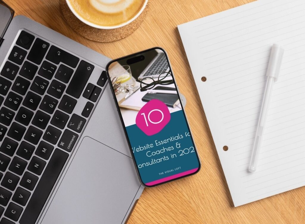 Laptop, phone, and notebook displaying the free website checklist for coaches and consultants